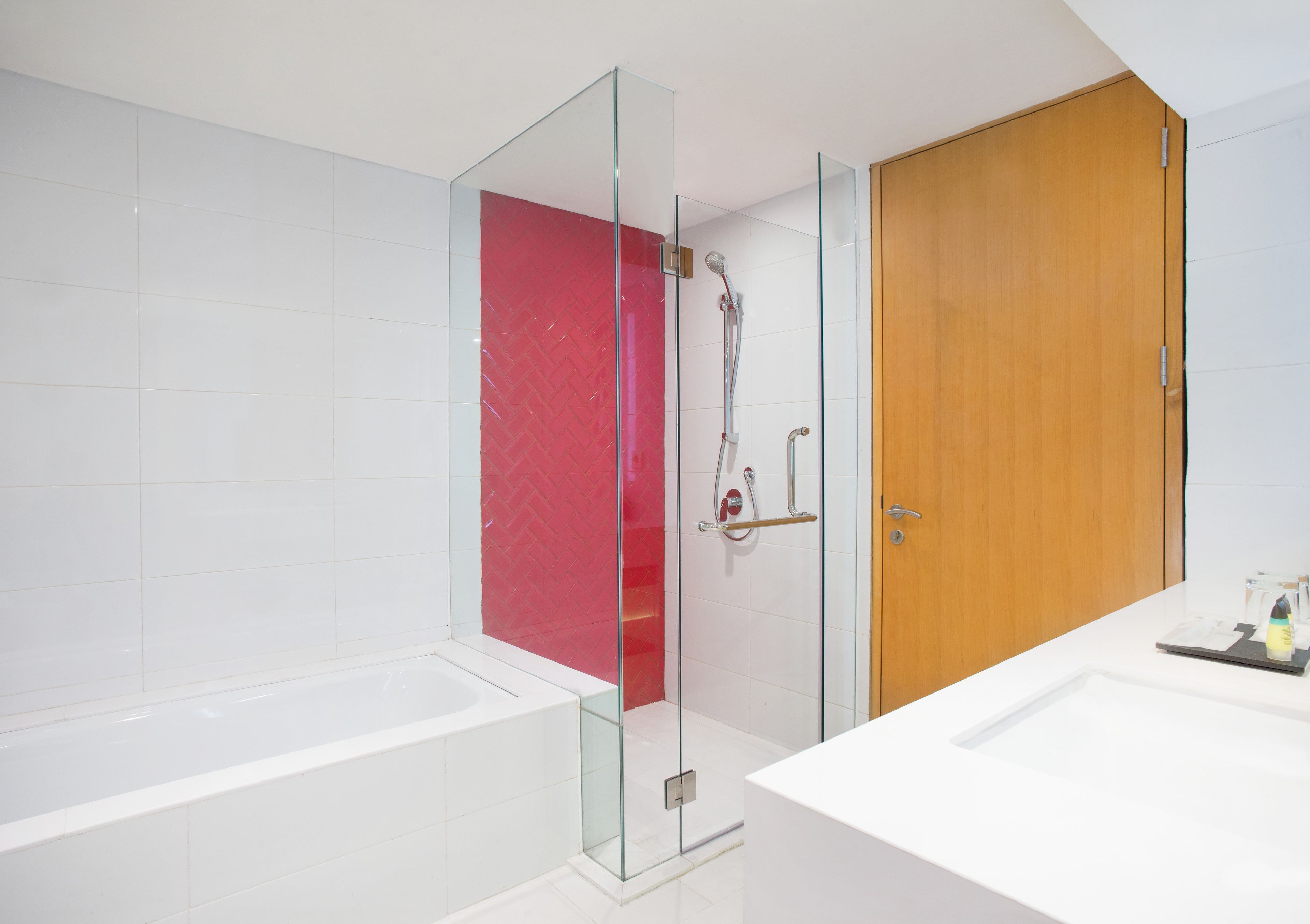 A modern bathroom with a glass-enclosed shower, a wooden door, and a white sink.