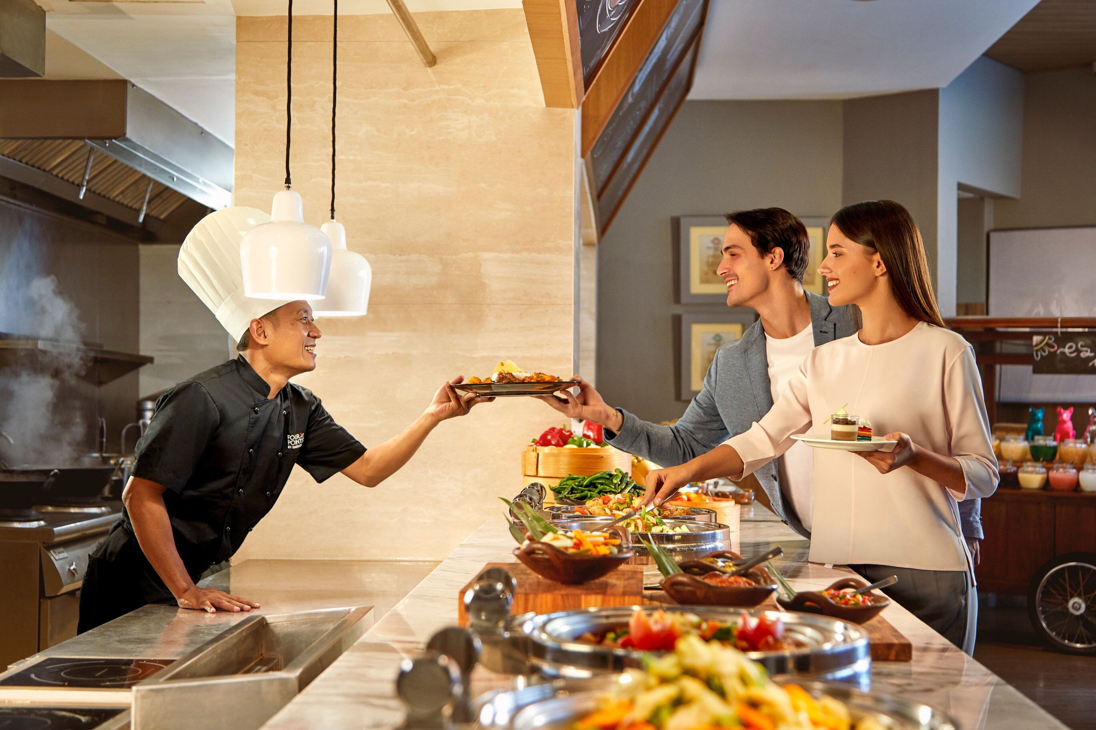 A buffet setup with various food items and a chef serving guests.