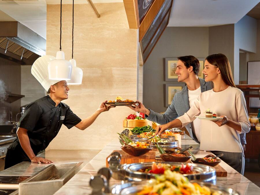 Montaje de bufé con diversas opciones de comida y un chef atendiendo a los comensales.