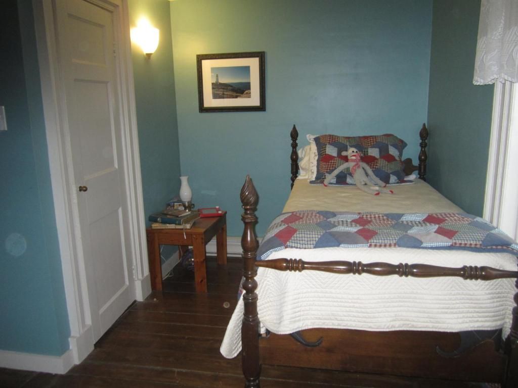 Une chambre à coucher avec un lit en bois, une table de chevet, une lampe et un tableau encadré au mur.