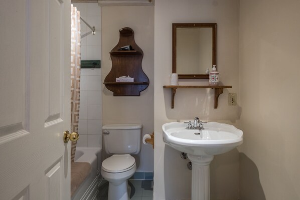 Un baño con inodoro, lavamanos y estantes de madera.