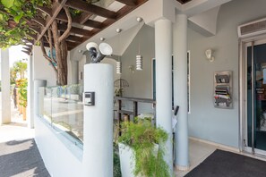 A modern building entrance with a glass door, a metal mailbox, and a potted plant. - Hotel Casa Jum (Santiago de los Caballeros)
