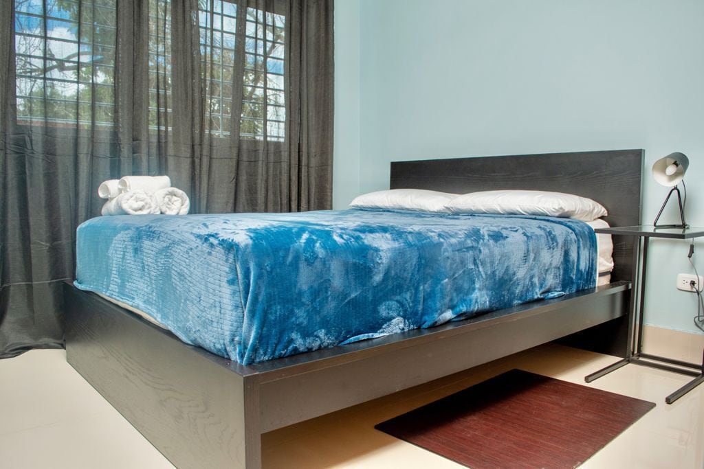 Een moderne slaapkamer met een bed, een donker hoofdbord en een bedlampje.