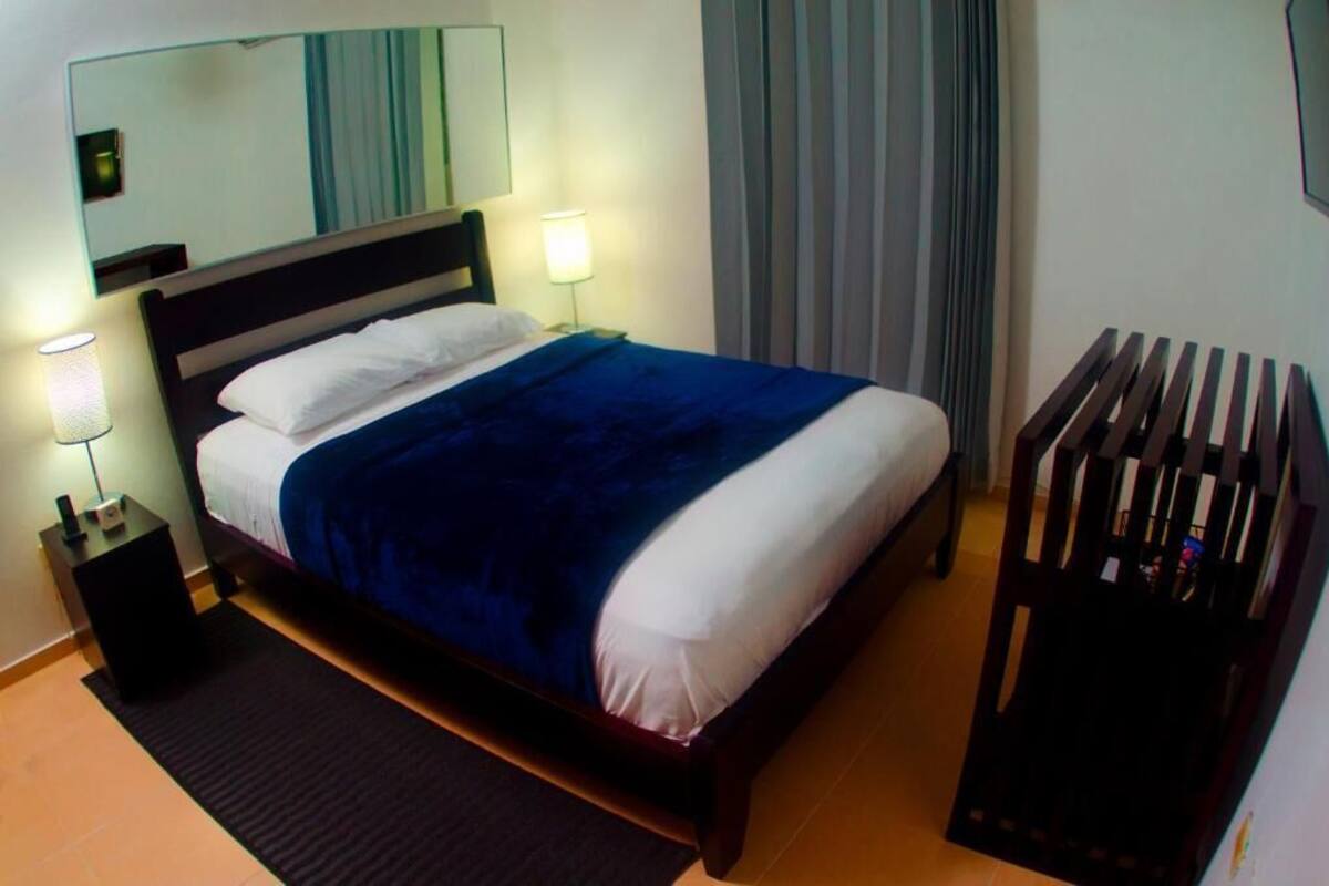 Ein Hotelzimmer mit Bett, Nachttischlampen, einem Nachttisch, einem Spiegel und einer Heizung.
