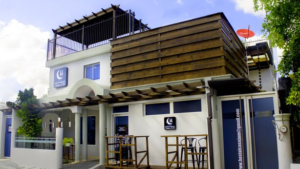 A two-story building with a wooden facade, a balcony, and a sign indicating a restaurant. - Hotel Casa Jum (Santiago de los Caballeros)