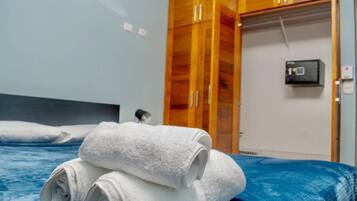 Een hotelkamer met een bed, een houten garderobe en een thermostaat aan de muur.