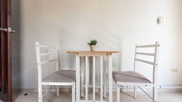 Una habitación con dos sillas blancas y una pequeña mesa con una planta en maceta.