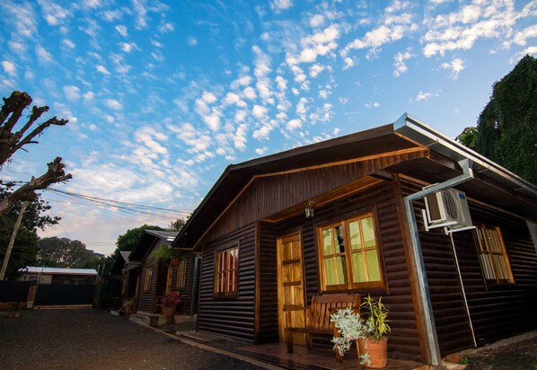 A rustic wooden cabin with a porch, large windows, and a basketball hoop.