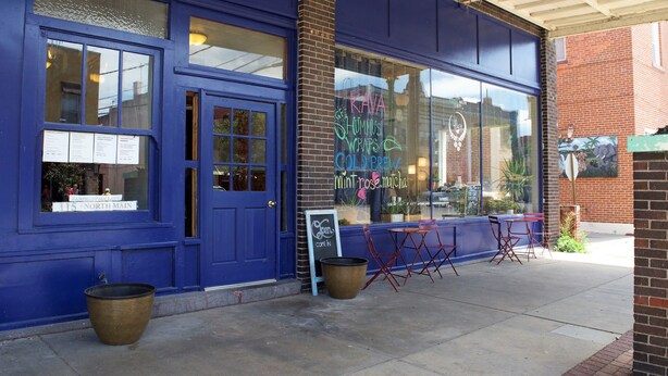 A blue storefront with a sign advertising hummus wraps and cold brew coffee. - The Landmark Inn (Fairfield)