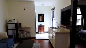 A compact living space with a kitchenette, a sofa, a coffee table, and a TV. - The Landmark Inn (Fairfield)
