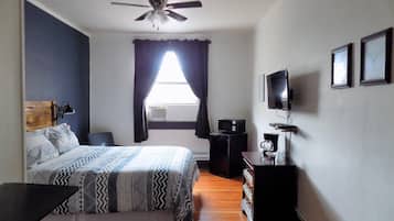 A bedroom with a bed, a ceiling fan, a TV, and a dresser.