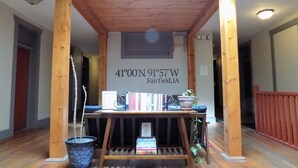 A reading area with a wooden table, books, a potted plant, and a sign indicating the location as 41°00'N 91°57'W Fairfield, IA. - The Landmark Inn (Fairfield)