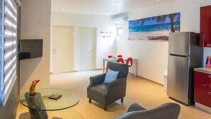 Een moderne woonkamer met een glazen salontafel, een grijze bank en een rode kast.