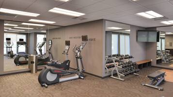 A gym with various exercise equipment, including treadmills, elliptical machines, and dumbbells.