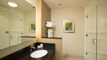 A modern bathroom with a black countertop sink, a large mirror, and a glass shower enclosure.