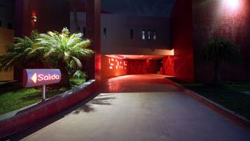 A hotel entrance with a sign reading "Salida" and a modern building with red lighting.
