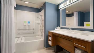 A modern bathroom with a bathtub, shower, and vanity.