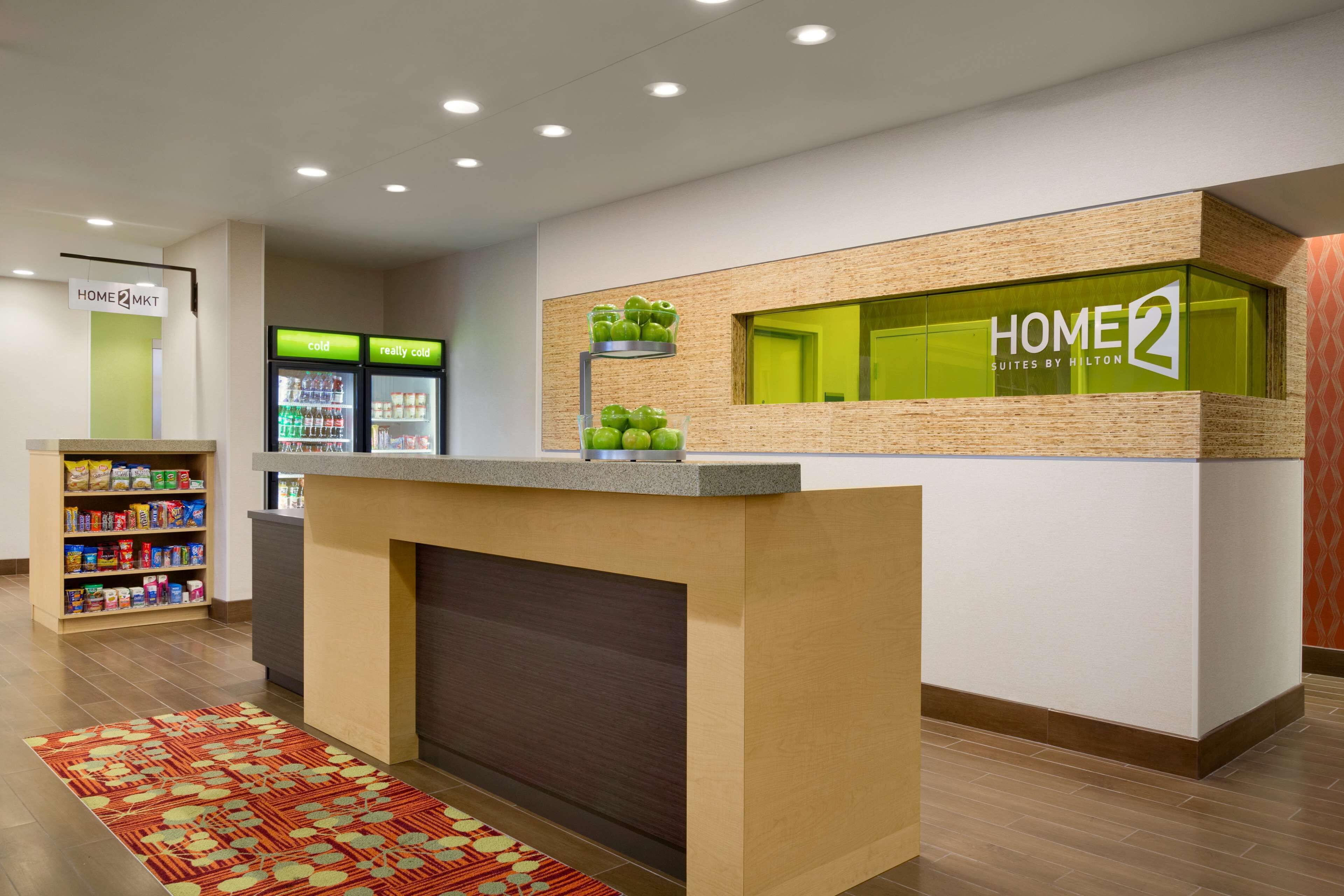 A hotel reception area with a counter, a refrigerator, and a snack shelf.