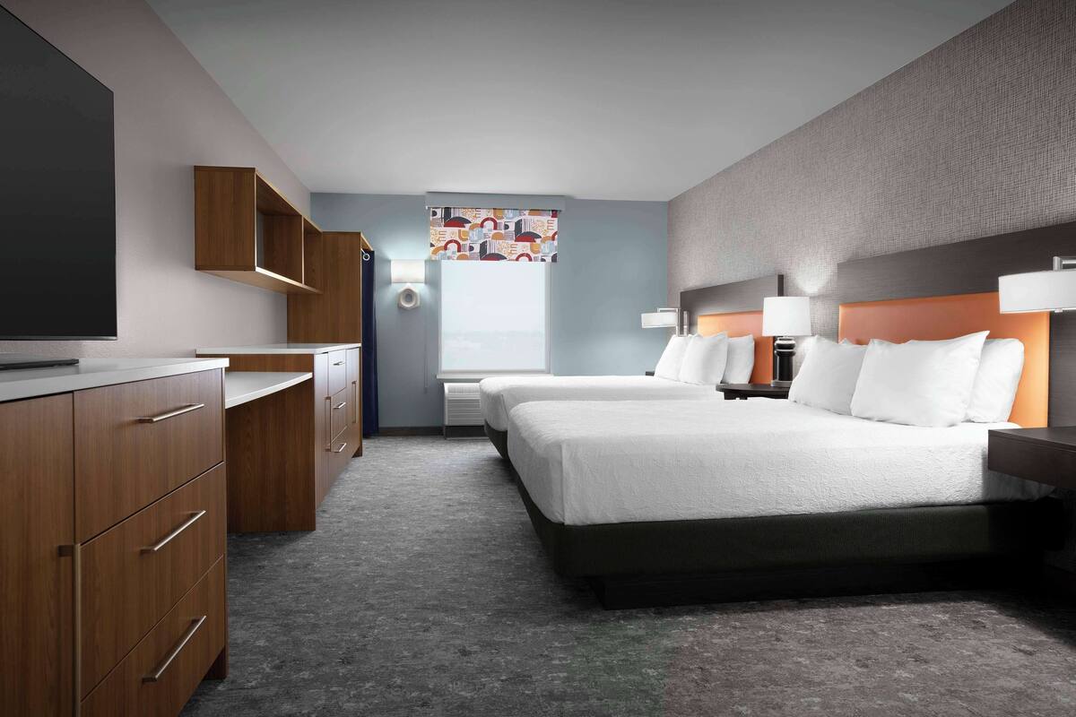 A hotel room with a large bed, a desk, and a television.