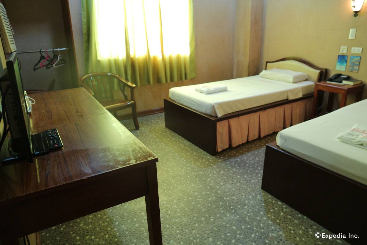 A hotel room with a bed, a desk with a telephone, and a chair.