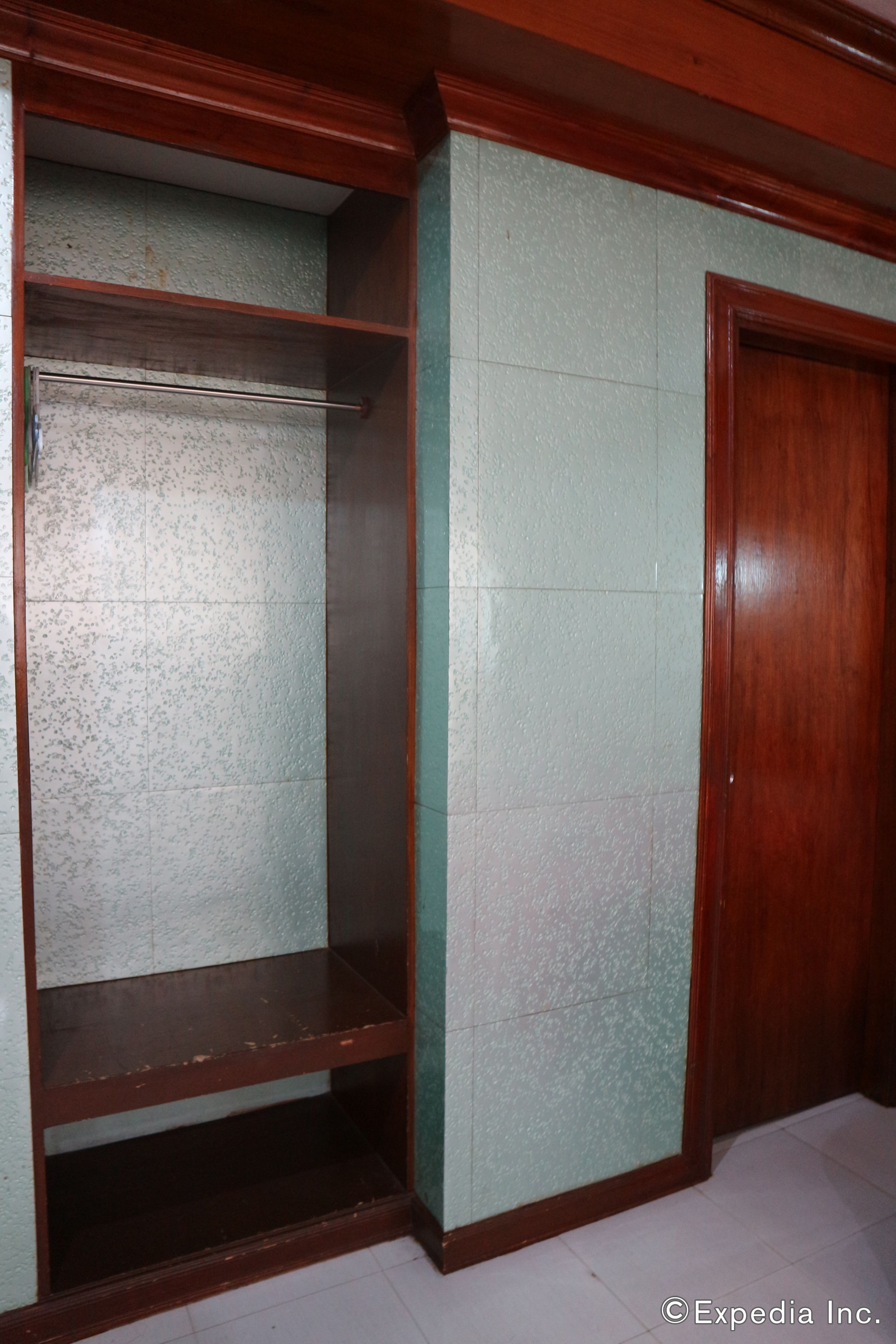 A corner of a room with a wooden wardrobe and a shelving unit against a green wall.