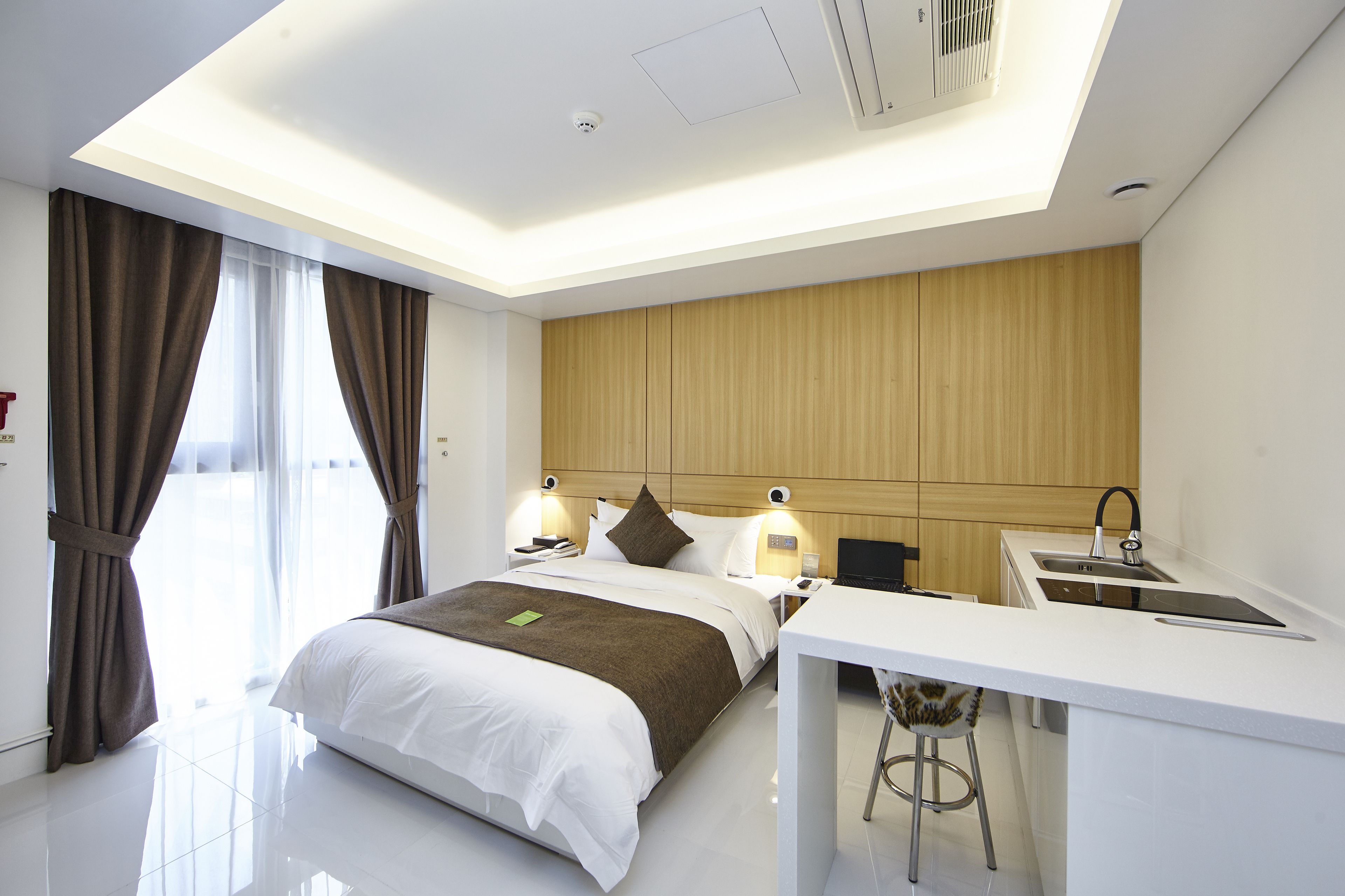Ein modernes Hotelzimmer mit einem großen Bett, einem Schreibtisch mit Spüle und Blick auf die Stadt.