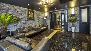 A modern lobby with a brick wall, leather sofas, a chandelier, and a polished marble floor. - Hotel Soulhada (Seoul)
