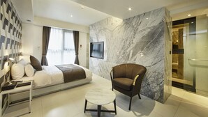 A modern hotel room with a bed, a chair, a TV, and a marble wall. - Hotel Soulhada (Seoul)