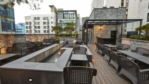An outdoor patio with seating and a water feature, surrounded by modern buildings. - Hotel Soulhada (Seoul)