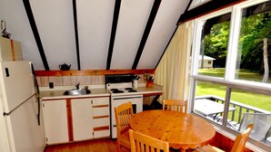 Une cuisine de taille réduite, dotée de meubles en bois, d’une cuisinière et d’une table à manger avec des chaises.
