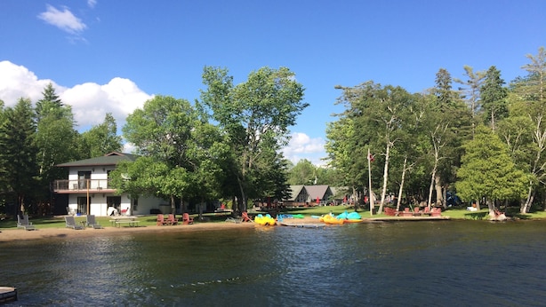 Une propriété au bord du lac, comprenant une maison, un espace extérieur aménagé et des bouées gonflables.