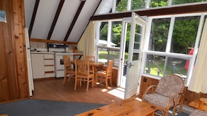 Un intérieur de chalet chaleureux, avec des meubles en bois, un coin repas et de grandes fenêtres donnant sur le paysage extérieur.