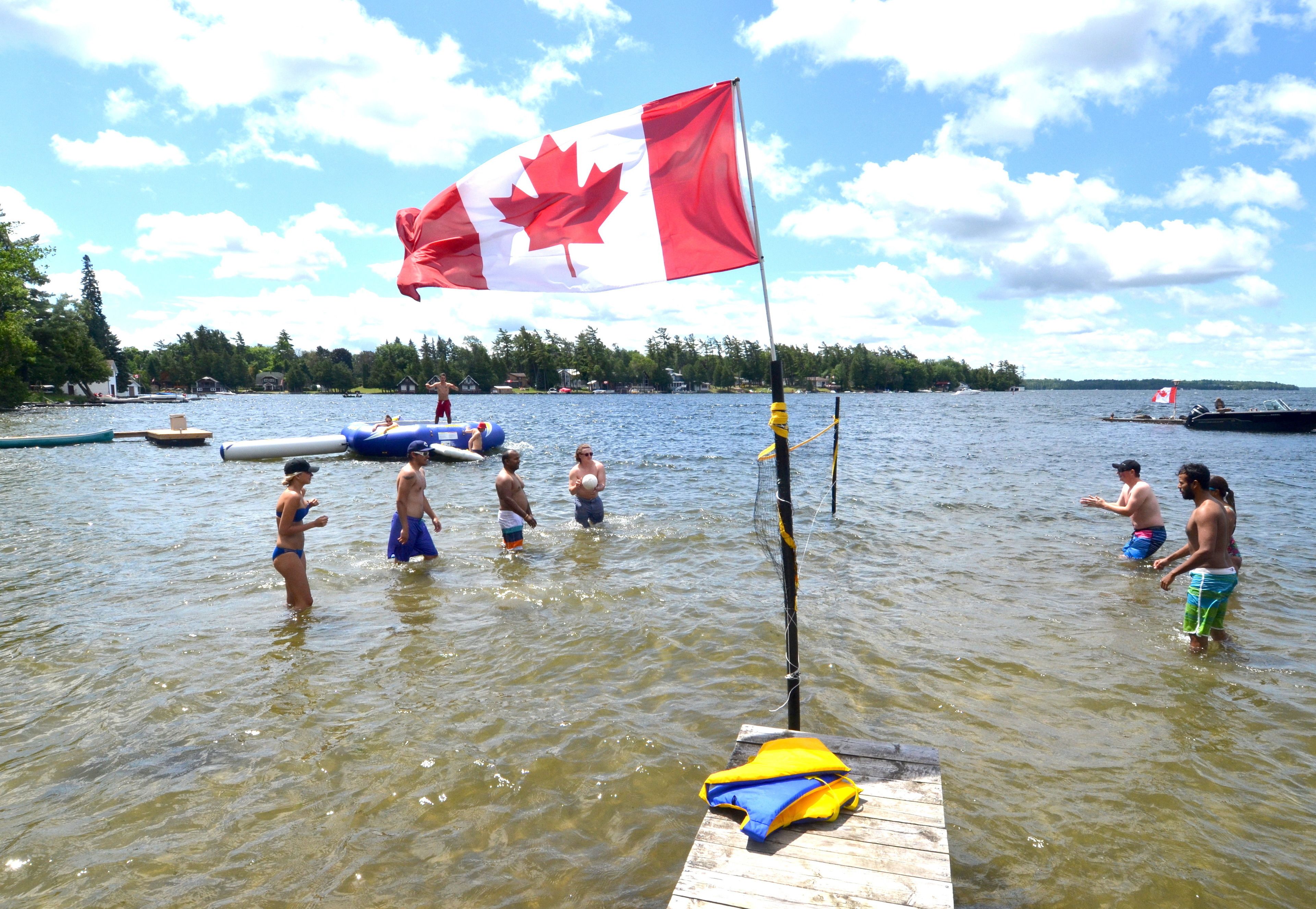 Un lac où des gens se baignent et une jetée avec un drapeau.