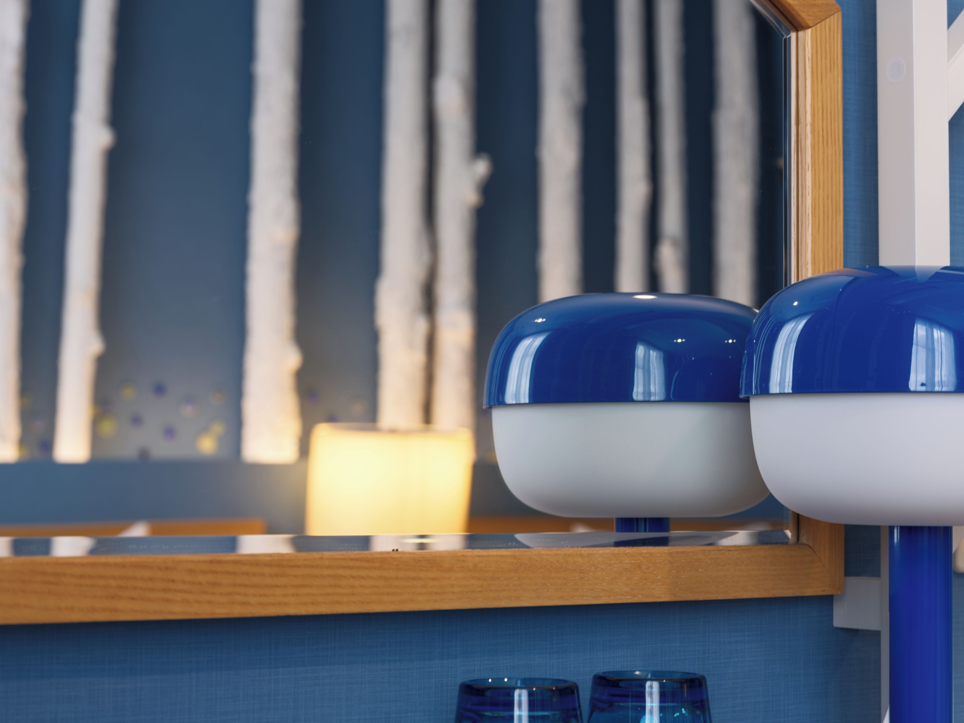 A bathroom with a mirror, two blue and white basins, and a wooden shelf.