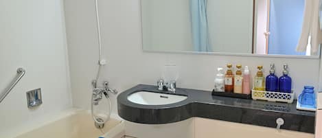 A bathroom with a bathtub, a sink, and a toilet. There are toiletries on the sink counter.