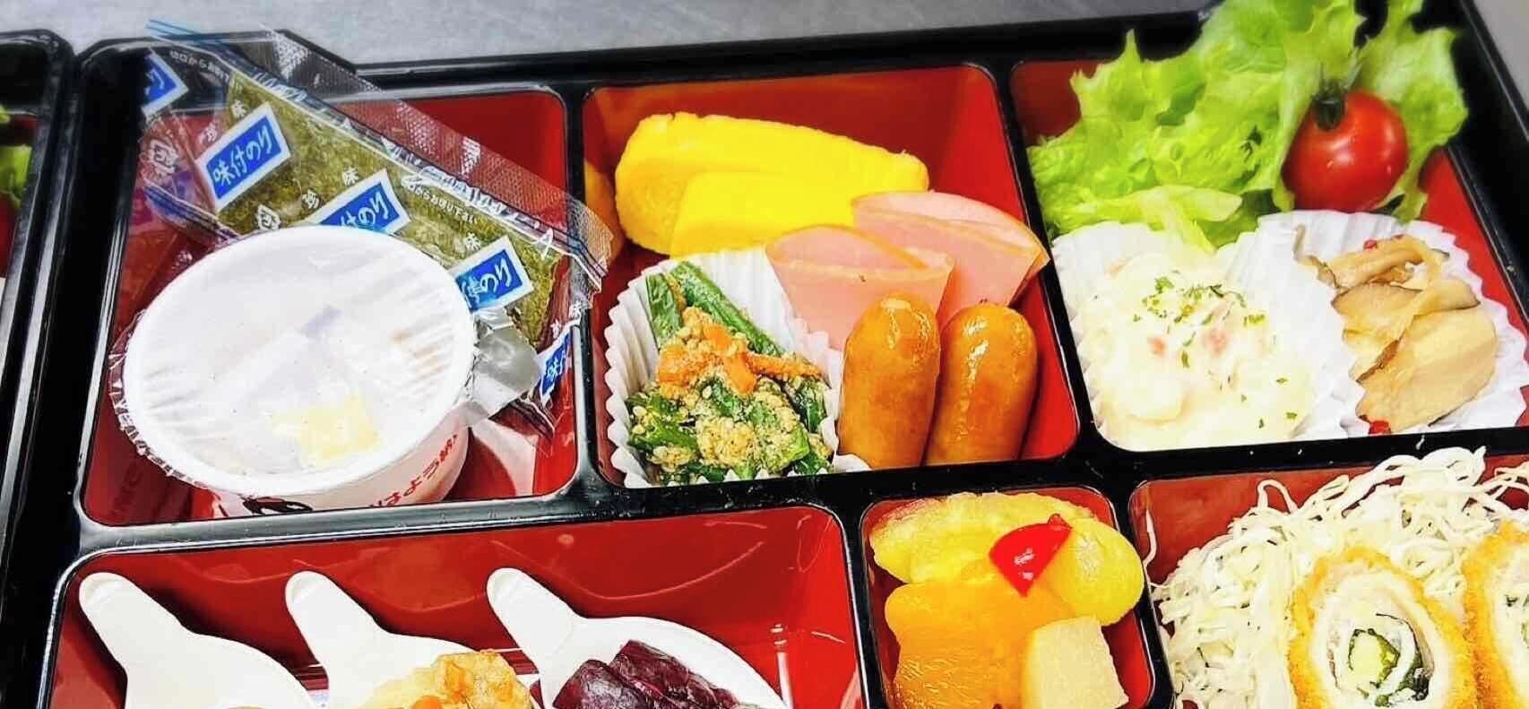 A bento box with various food items including rice, vegetables, and meat.