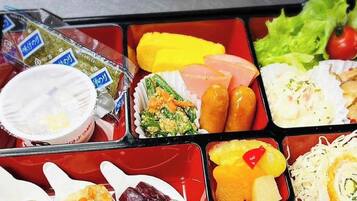 Una caja bento con diferentes alimentos, como arroz, verduras y carne.