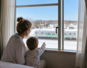 A woman and a child sitting by a window with a view of a train. - Hotel Lavenir (Biei)
