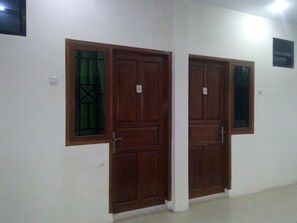 A hallway with two wooden doors, each with a window and a number plate. - Living Peace House (Manado)