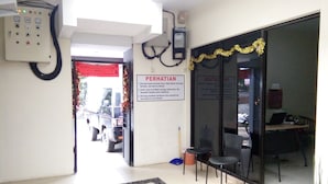 A reception area with a signboard, a control panel, and a seating area with chairs and a table. - Living Peace House (Manado)