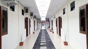 A long hallway with multiple doors, air conditioning units, and potted plants. - Living Peace House (Manado)