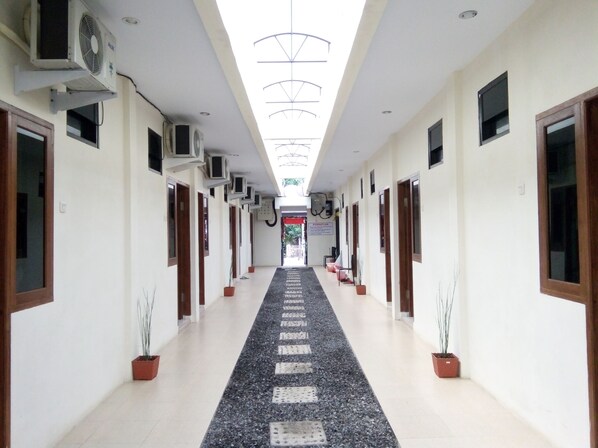 A long hallway with multiple doors, air conditioning units, and potted plants. - Living Peace House (Manado)