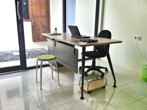A small office space with a desk, chair, and stool. - Living Peace House (Manado)
