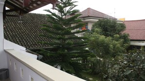 Un edificio con techo de tejas y un balcón con vistas a un jardín con diversos árboles.