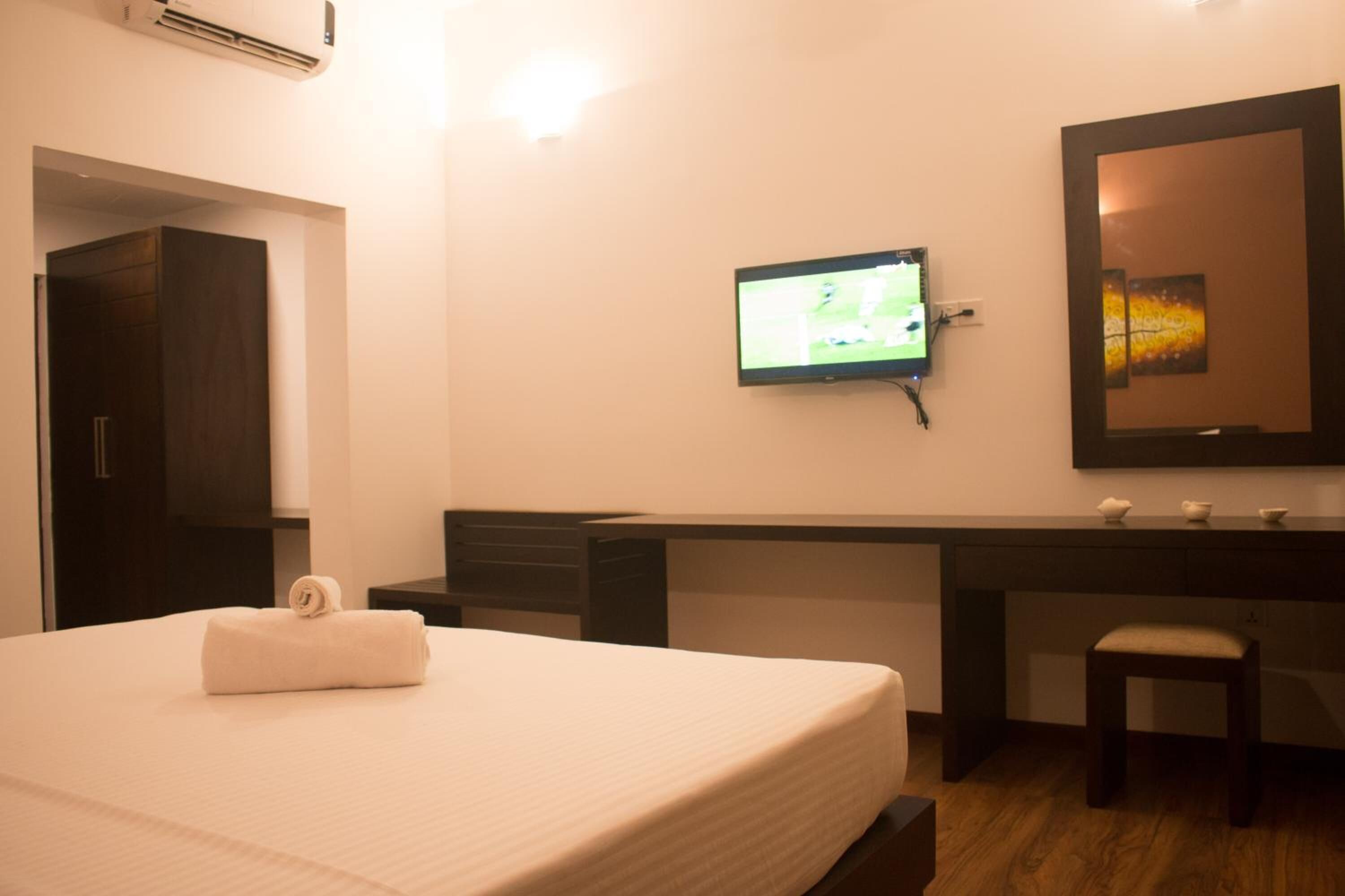 Een hotelkamer met een bed, een bureau, een televisie en een spiegel.
