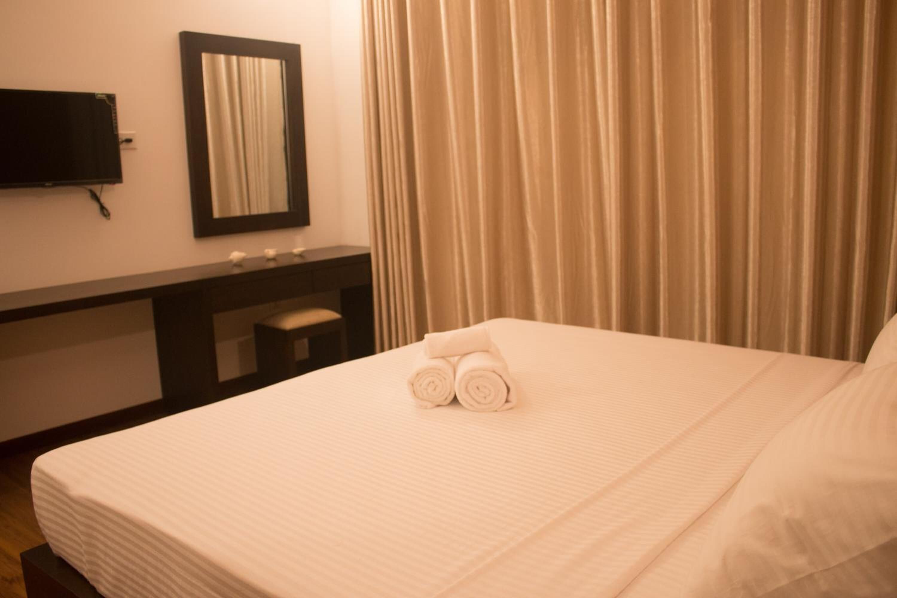 A hotel room with a bed, a bedside table, a mirror, and a TV.