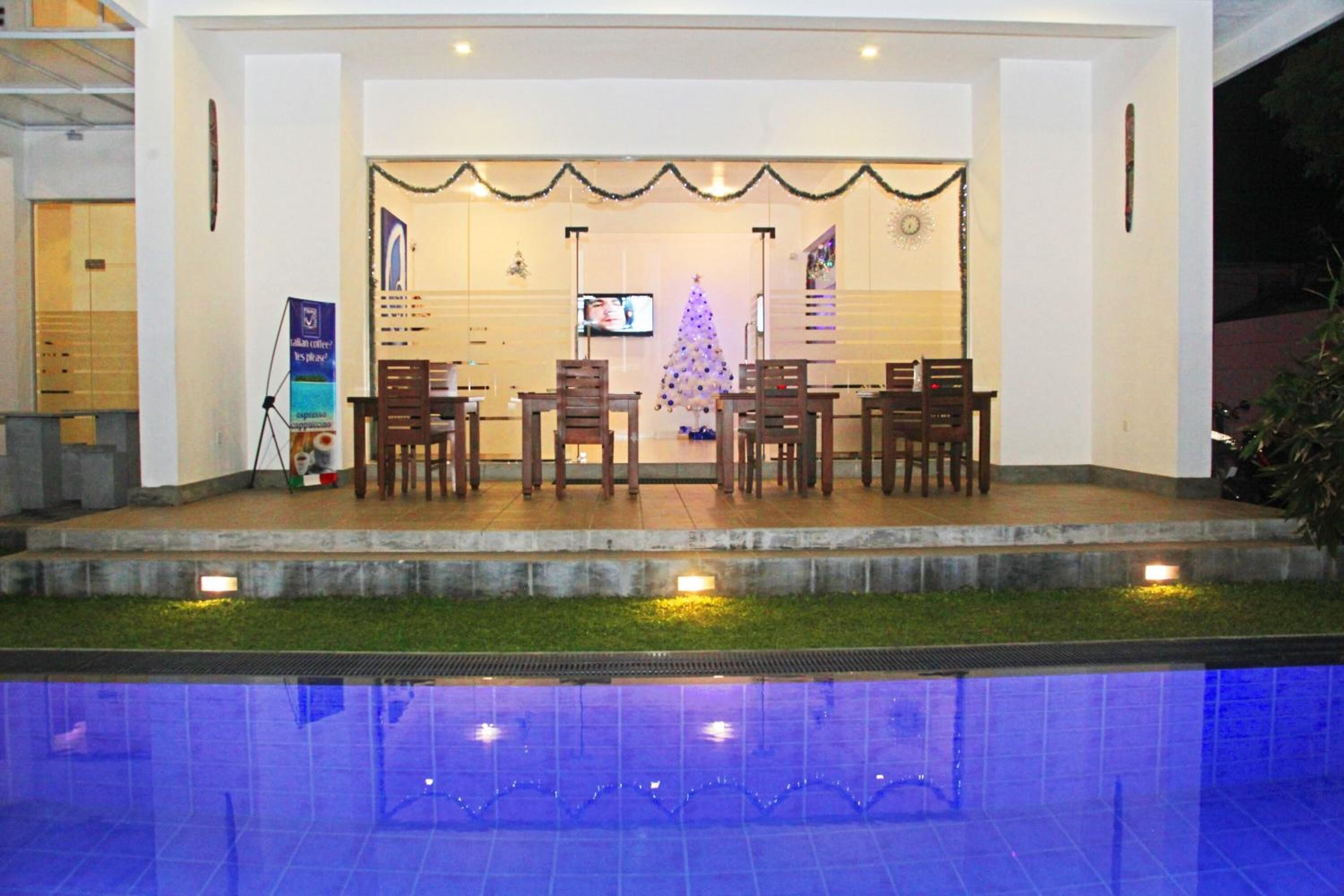 A reception area with a Christmas tree, wooden chairs, and a television screen.