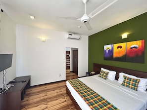A hotel room with a bed, a desk, a ceiling fan, and a wall-mounted air conditioner. - The Suite 262 (Negombo)