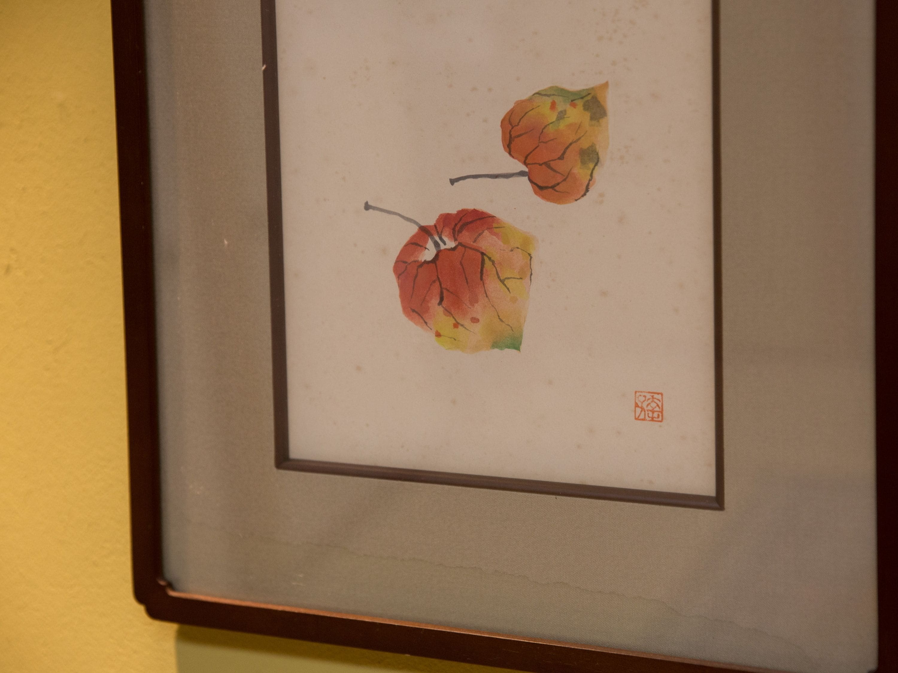 A framed artwork of two leaves on a wall.