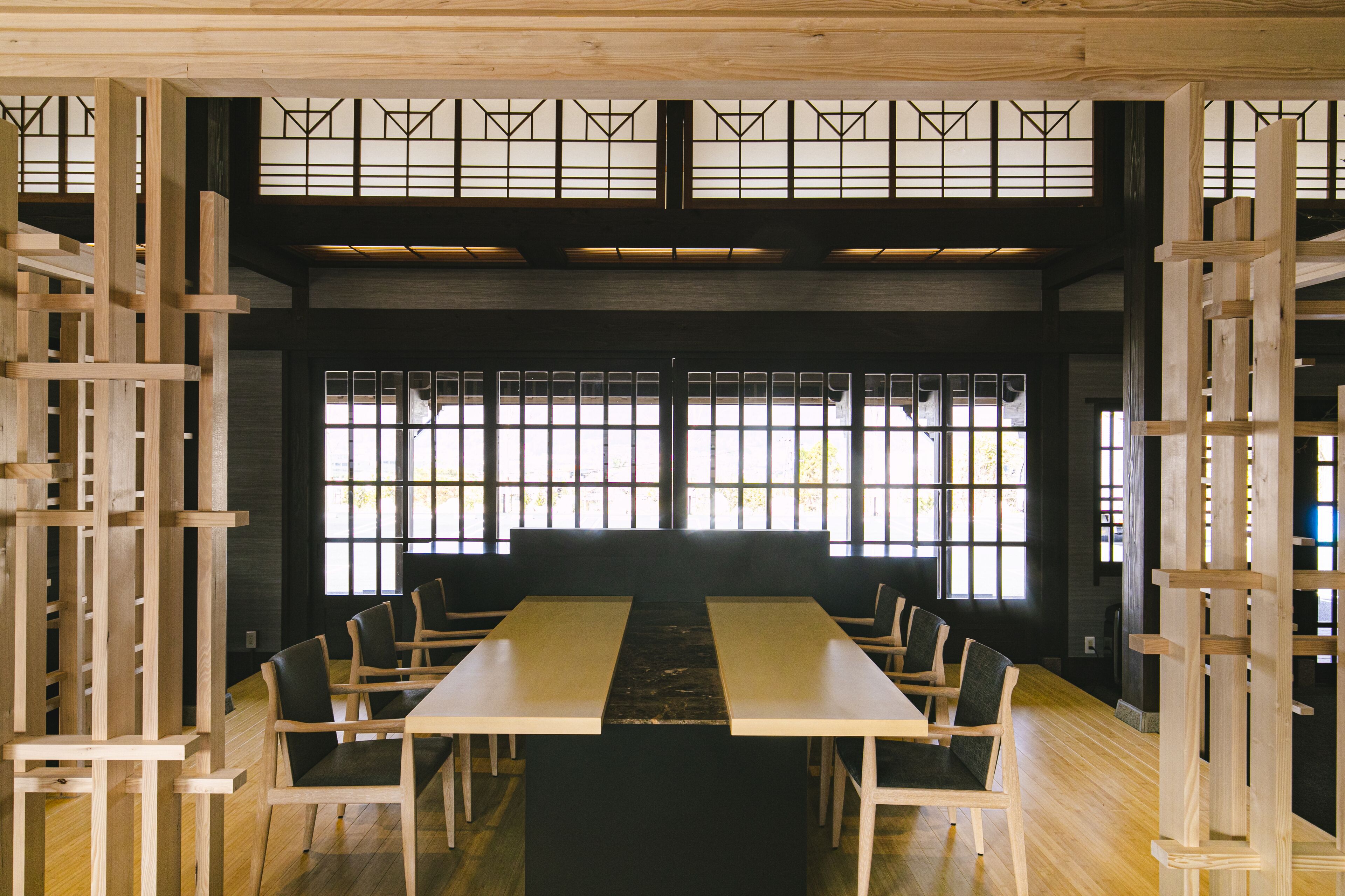 A traditional Japanese-style room with tatami flooring, a low table, and wooden chairs.